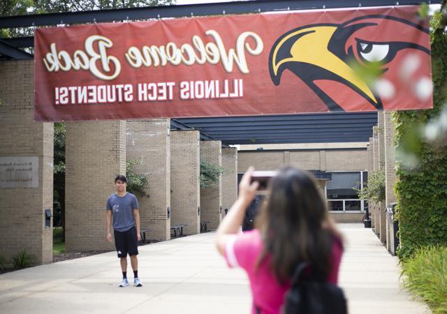 A student has his picture taken under a banner during move-in day